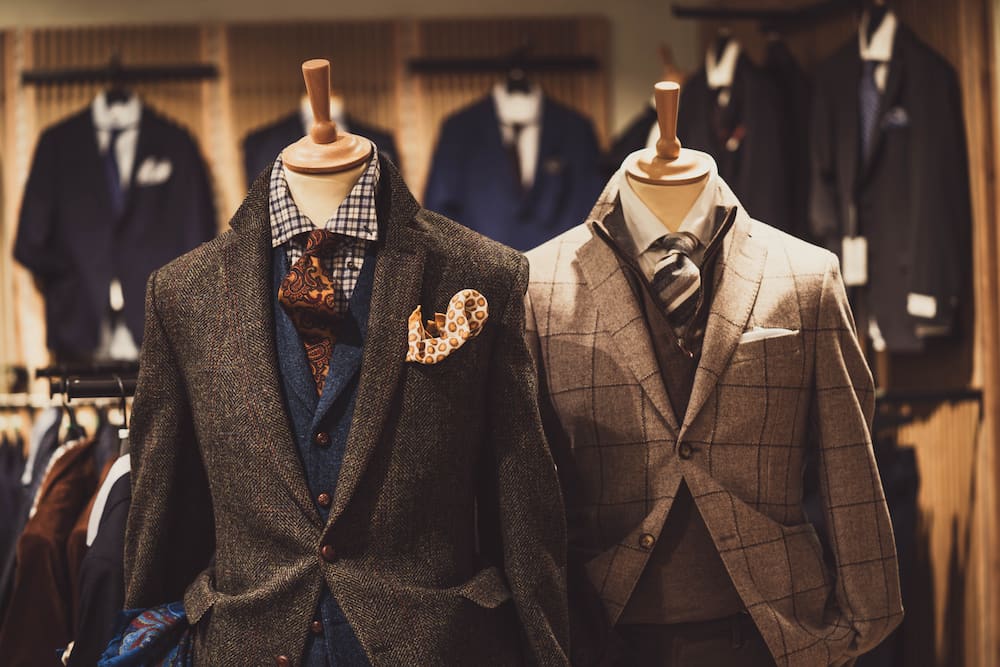A pair of fancy suits on displayed in a store.
