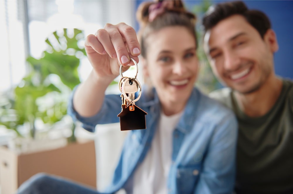 couple holding up keys to their new house-they moved in using moving tips