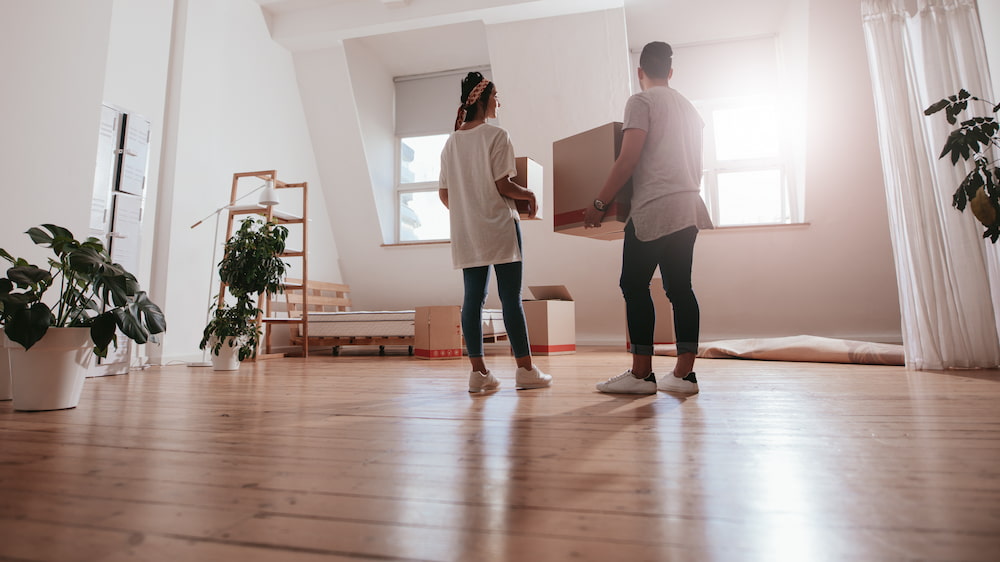 couple standing with boxes in an open room while combining households