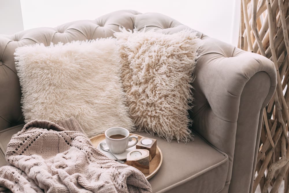 cozy blush couch with pillows, blanket and a cup of coffee 