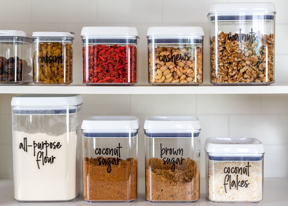 a variety of ingredients in clear containers in an organized pantry