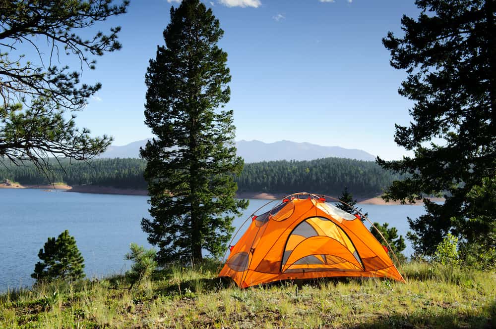 orange tent in the mountains overlooking the water