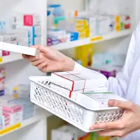 Someone stocking medicine in a pharmacy.