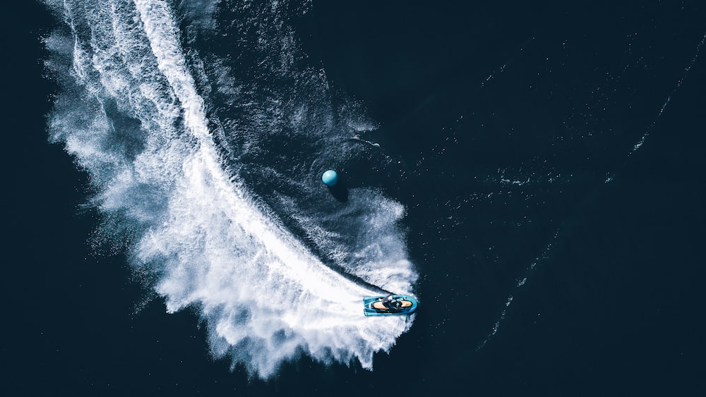 an overhead photograph of a jet ski carving a turn on the water