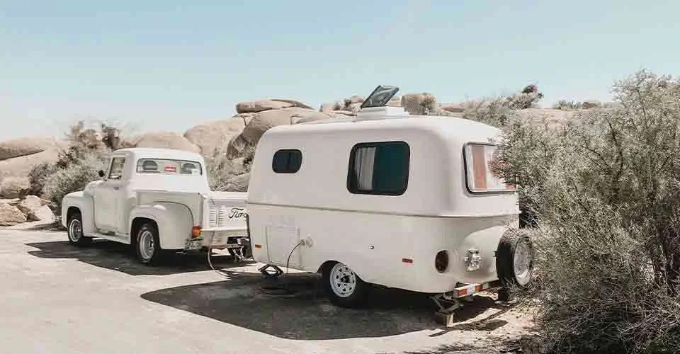 white truck pulling trailer in the dessert after being stored