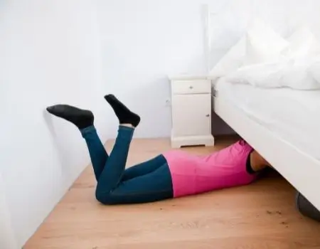 woman cleaning under bed