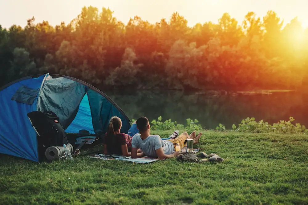 couple camping with camping essentials like a tent, a blanket and more