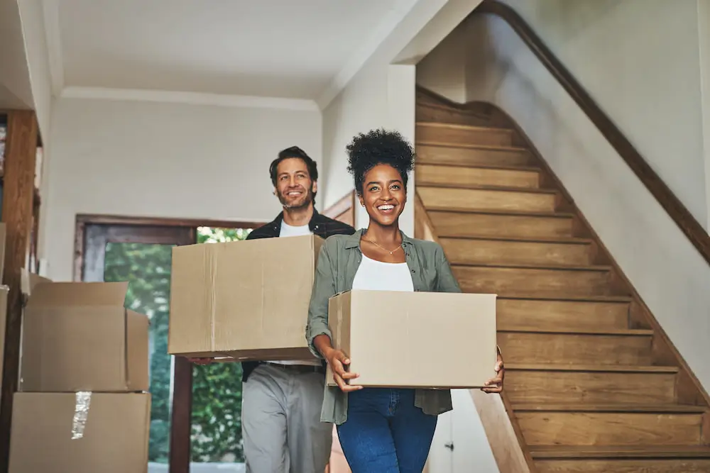 a couple waling with boxes inside while combing households