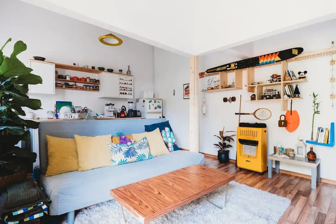 a bright and vibrant studio apartment with a blue couch, plants and a variety of decorations