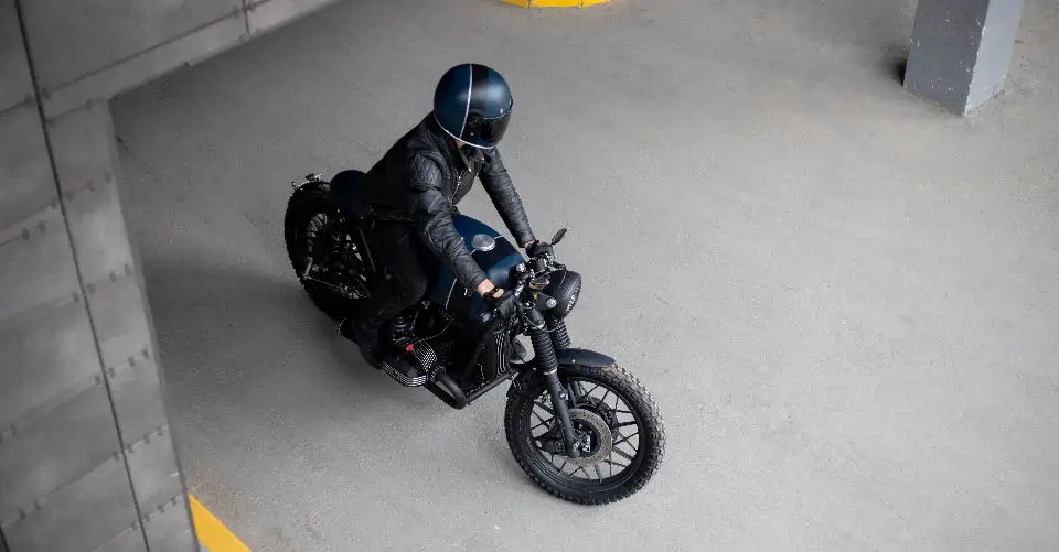 A black-clad motorcycle rider rides his bike out of a storage unit