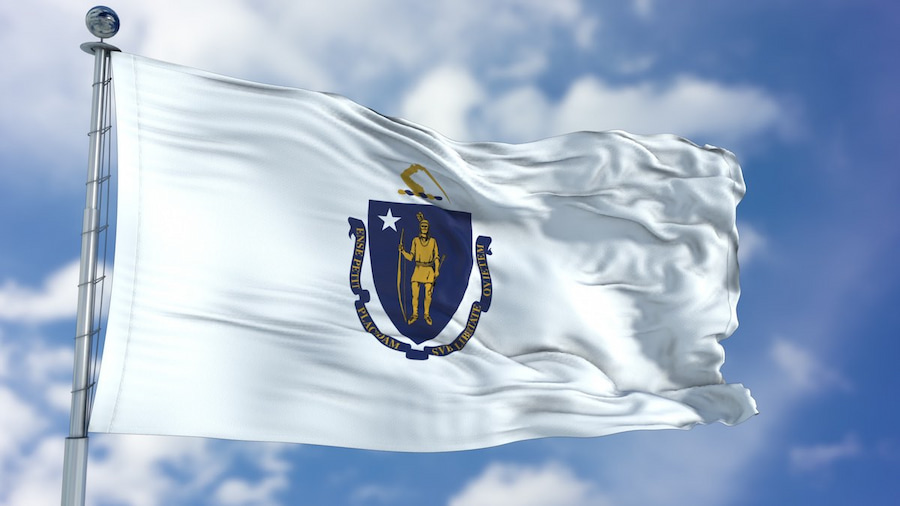 Massachusetts state flag waving against clear blue sky