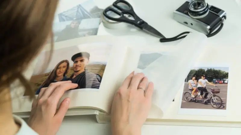 A woman holding a scrapbook open to photos.