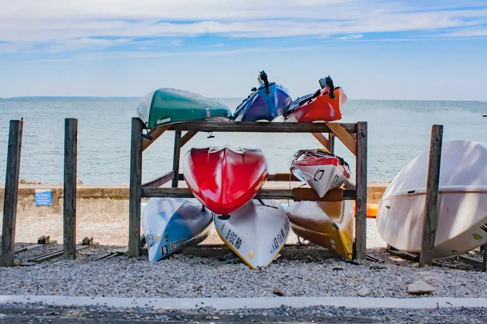 multiple, colorful kayaks on an outdoor kayak storage rack