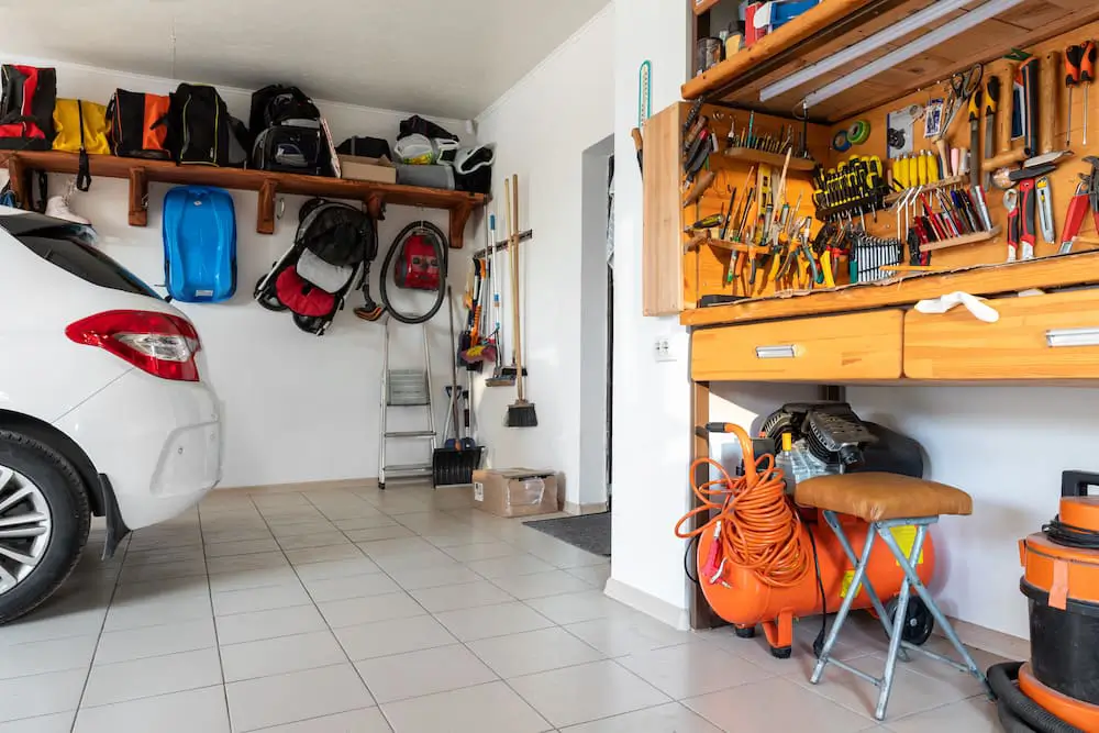 corner of a decluttered and organized garage with a workbench, shelving and car